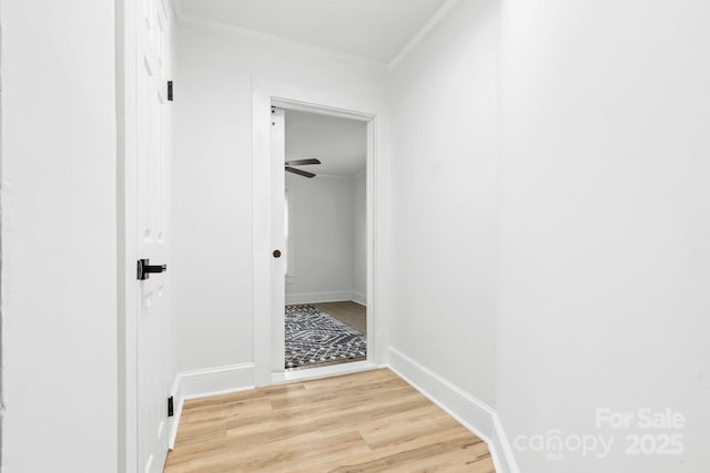 corridor featuring baseboards, light wood-style flooring, and crown molding