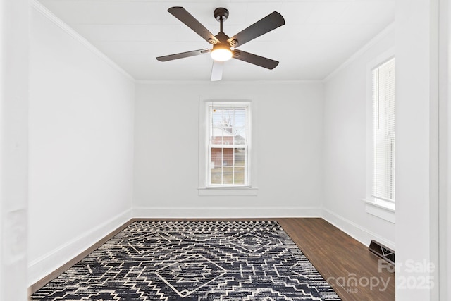 empty room featuring wood finished floors, a ceiling fan, baseboards, and ornamental molding