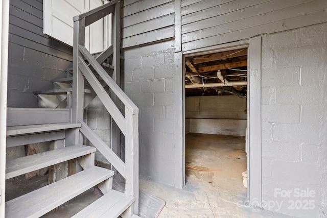 staircase featuring concrete floors and concrete block wall