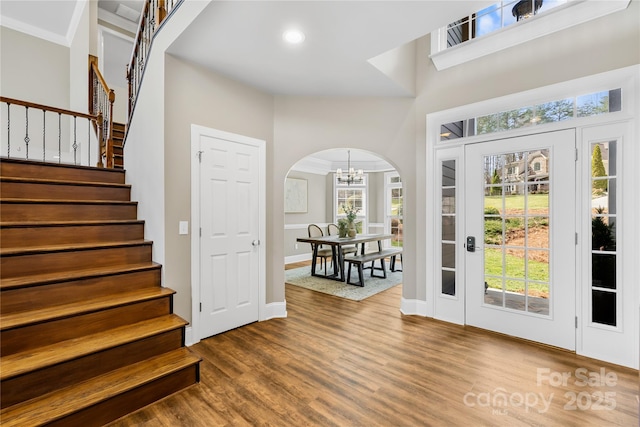 entrance foyer with a wealth of natural light, a chandelier, wood finished floors, and stairs