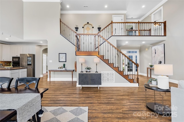 living room with crown molding, baseboards, stairway, wood finished floors, and arched walkways