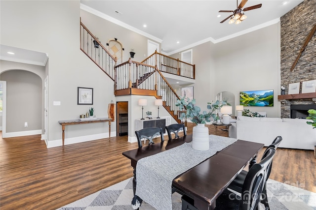 dining room with arched walkways, wood finished floors, stairs, and ornamental molding