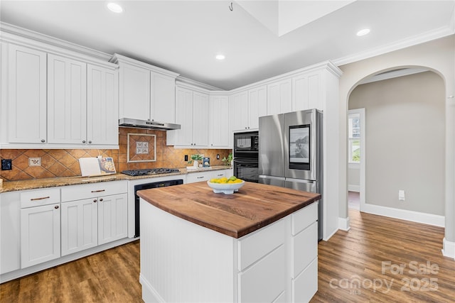 kitchen with dark wood-style flooring, arched walkways, butcher block countertops, black appliances, and under cabinet range hood