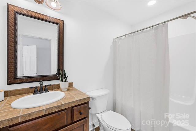 bathroom featuring toilet, vanity, and a shower with curtain