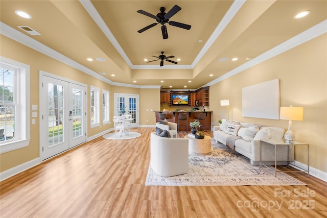 living area featuring light wood-type flooring, visible vents, a tray ceiling, recessed lighting, and french doors