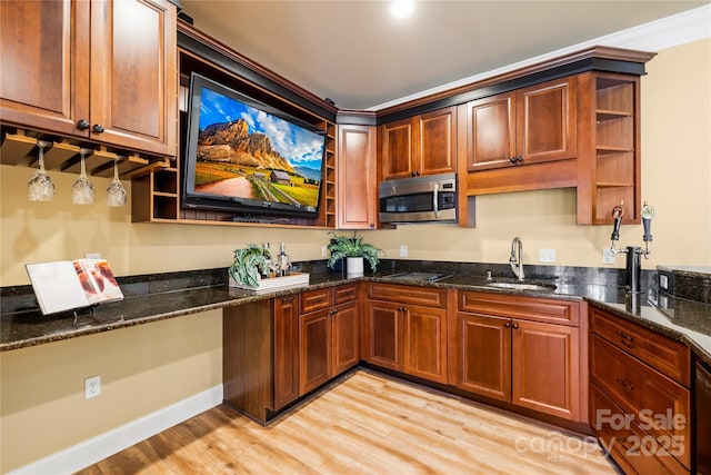 kitchen featuring light wood finished floors, dark stone counters, open shelves, a sink, and stainless steel microwave