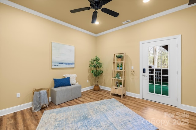 living area featuring crown molding, wood finished floors, visible vents, and baseboards