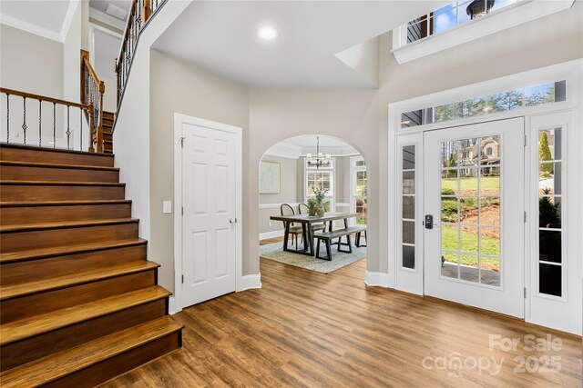 228 Wildwood Cove Dr, Mooresville, NC 28117 - entryway with a chandelier, wood finished floors, stairway, arched walkways, and healthy amount of natural light