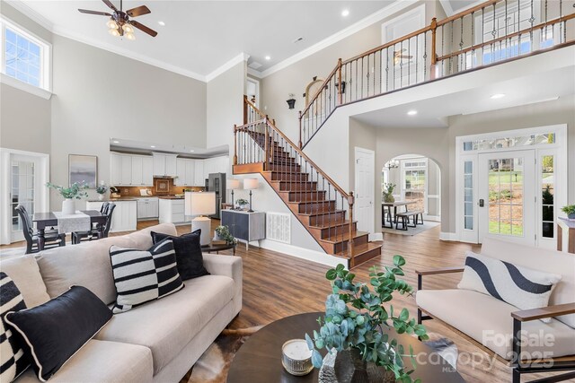 228 Wildwood Cove Dr, Mooresville, NC 28117 - living room featuring a towering ceiling, ornamental molding, stairs, a ceiling fan, and arched walkways