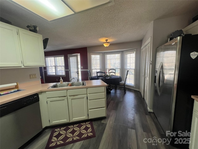 kitchen featuring plenty of natural light, a peninsula, stainless steel appliances, light countertops, and a sink