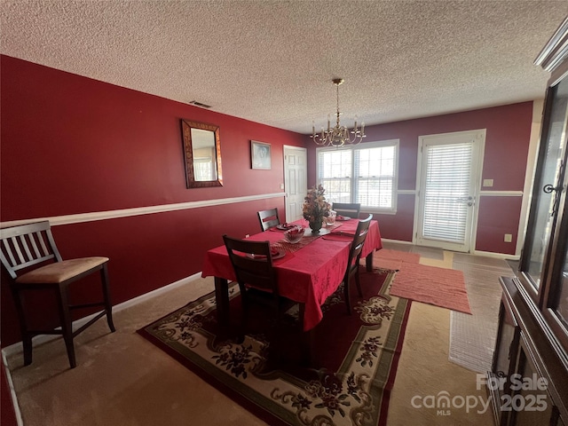 carpeted dining space with an inviting chandelier, baseboards, visible vents, and a textured ceiling