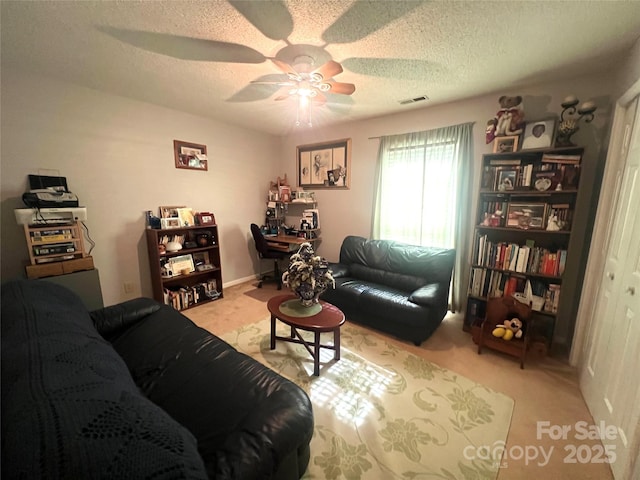 living room with a textured ceiling, ceiling fan, light carpet, and visible vents