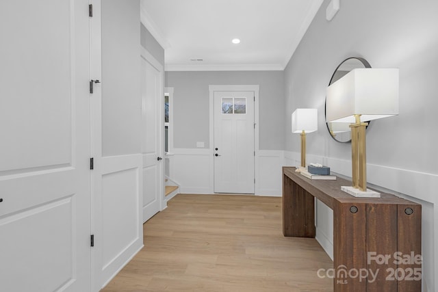 entrance foyer featuring a wainscoted wall, crown molding, light wood-style floors, a decorative wall, and recessed lighting