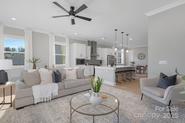 living area featuring recessed lighting, crown molding, light wood-style flooring, and ceiling fan