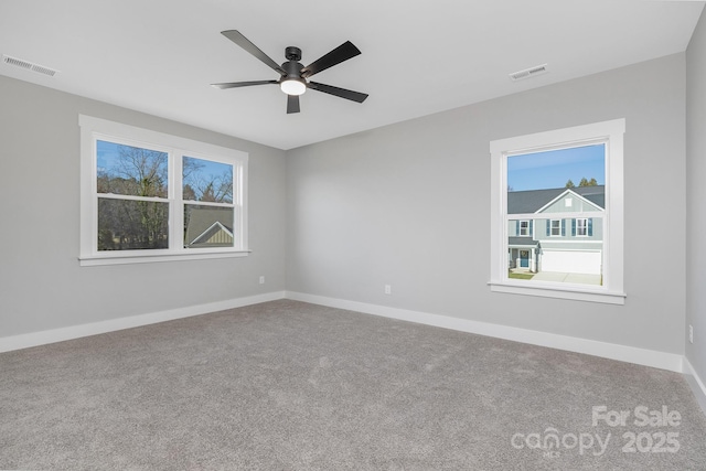 carpeted spare room with baseboards, visible vents, and a ceiling fan