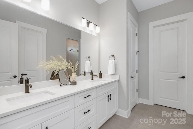 bathroom with double vanity, baseboards, and a sink