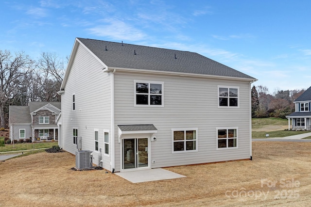 back of property featuring a shingled roof, cooling unit, and a lawn