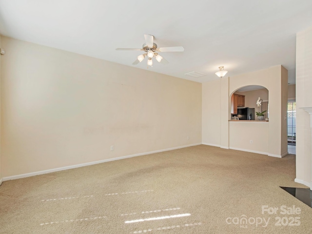 unfurnished living room with baseboards, arched walkways, ceiling fan, and carpet flooring