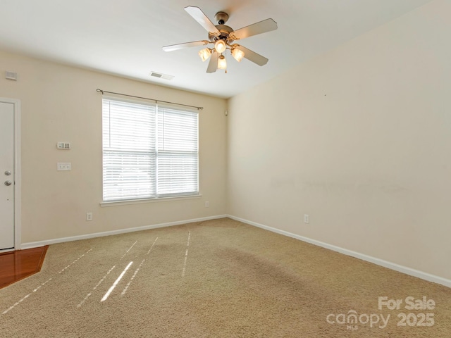 empty room featuring visible vents, ceiling fan, carpet, and baseboards