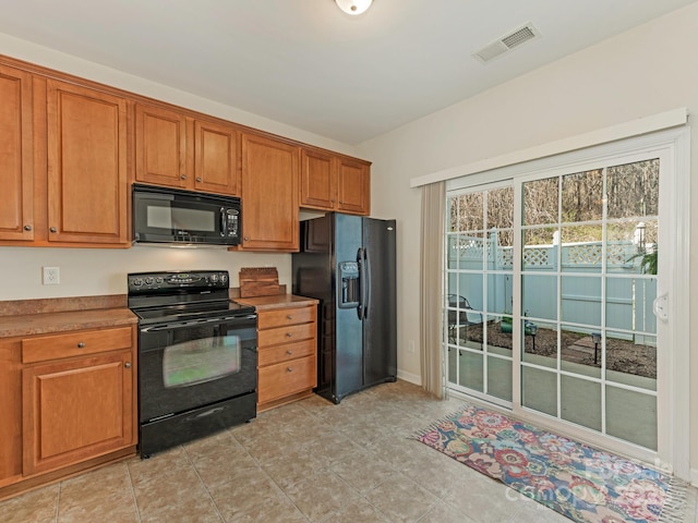 kitchen with brown cabinetry, visible vents, and black appliances