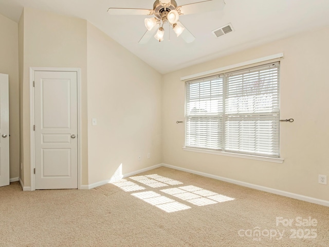 carpeted empty room with visible vents, baseboards, lofted ceiling, and a ceiling fan