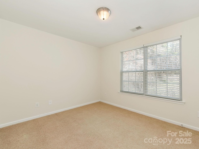 carpeted spare room featuring visible vents and baseboards