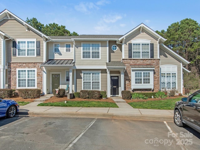 townhome / multi-family property featuring uncovered parking and stone siding