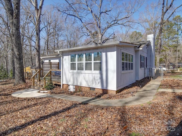 view of property exterior featuring crawl space, a chimney, fence, and board and batten siding