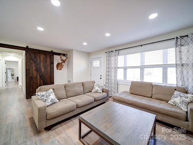 living area with light wood-type flooring, a barn door, and recessed lighting