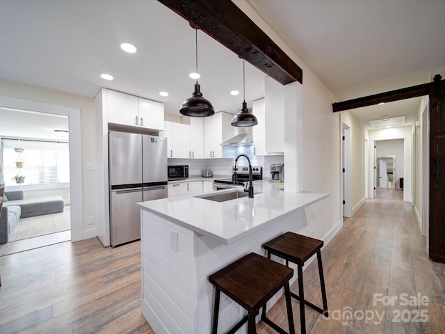 kitchen with pendant lighting, stainless steel appliances, white cabinetry, a peninsula, and a kitchen bar