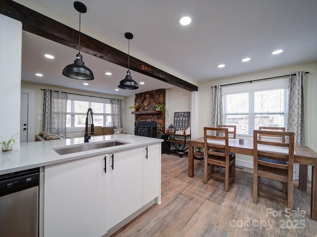 kitchen featuring light countertops, hanging light fixtures, open floor plan, a sink, and dishwasher