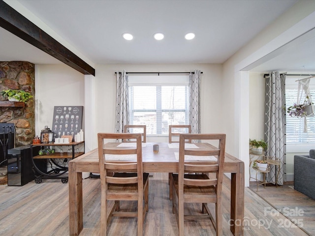 dining room featuring a stone fireplace, wood finished floors, and recessed lighting