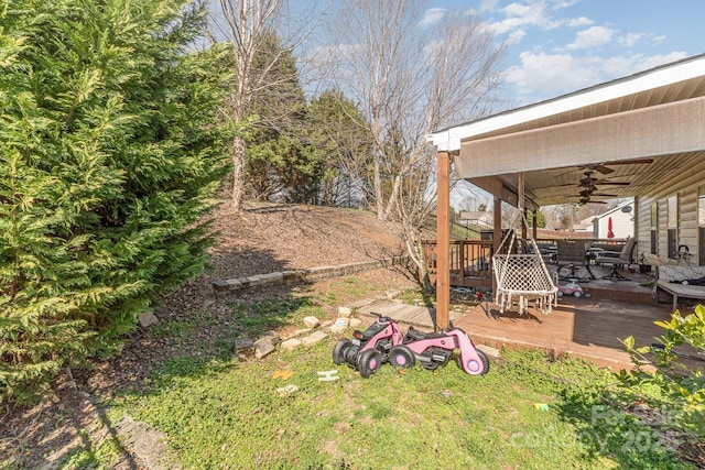 view of yard featuring ceiling fan, outdoor dining area, and a wooden deck