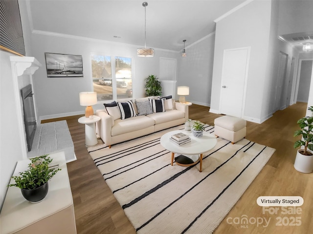 living room featuring ornamental molding, wood finished floors, a glass covered fireplace, and baseboards