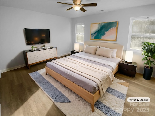 bedroom featuring a ceiling fan, visible vents, baseboards, and wood finished floors