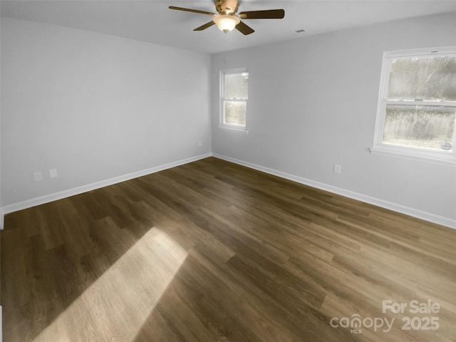 unfurnished room featuring dark wood-style floors, a ceiling fan, and baseboards