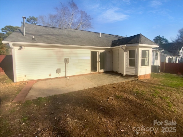 rear view of house with roof with shingles and a patio area