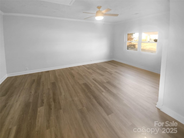 spare room with attic access, baseboards, a ceiling fan, ornamental molding, and wood finished floors