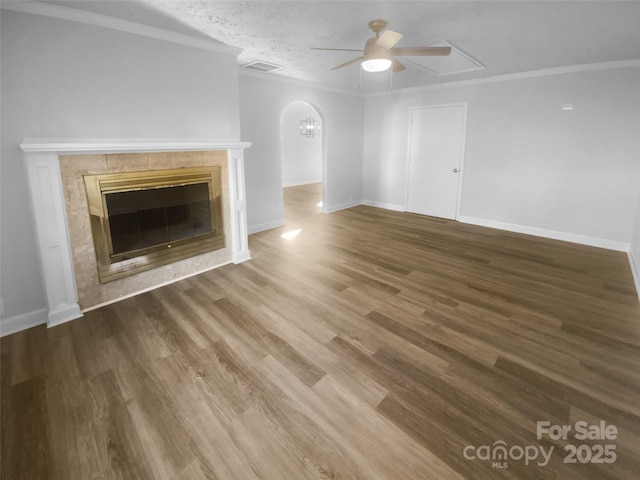 unfurnished living room featuring crown molding, visible vents, dark wood-type flooring, and a tiled fireplace