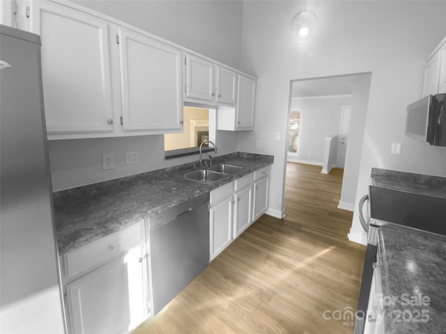 kitchen featuring black dishwasher, white cabinets, a sink, wood finished floors, and baseboards