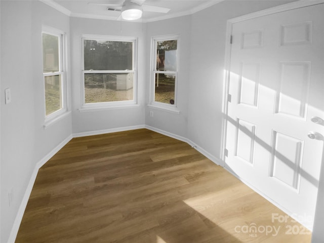 empty room featuring visible vents, dark wood-type flooring, ornamental molding, a ceiling fan, and baseboards