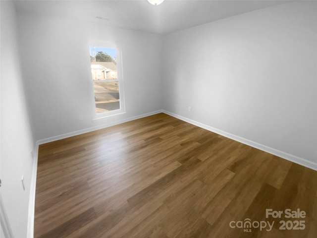 empty room featuring dark wood-style floors and baseboards