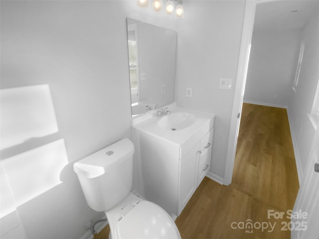 half bath with vanity, toilet, and wood finished floors