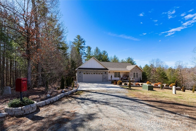 view of front of home with driveway, stone siding, and a garage