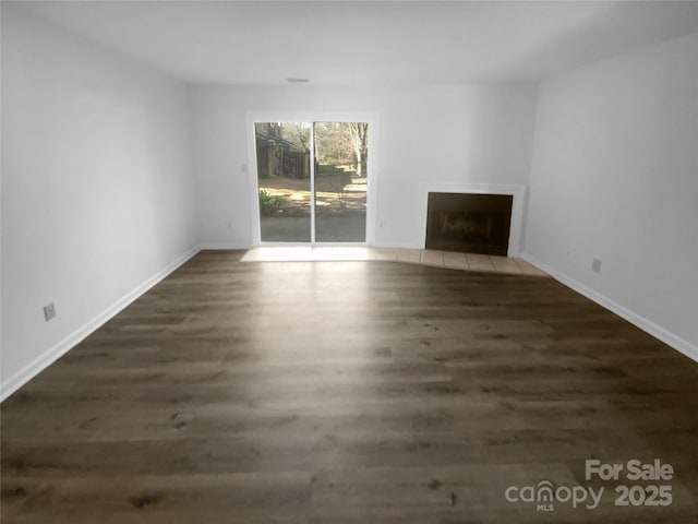 unfurnished living room with a fireplace with flush hearth, baseboards, and dark wood-type flooring