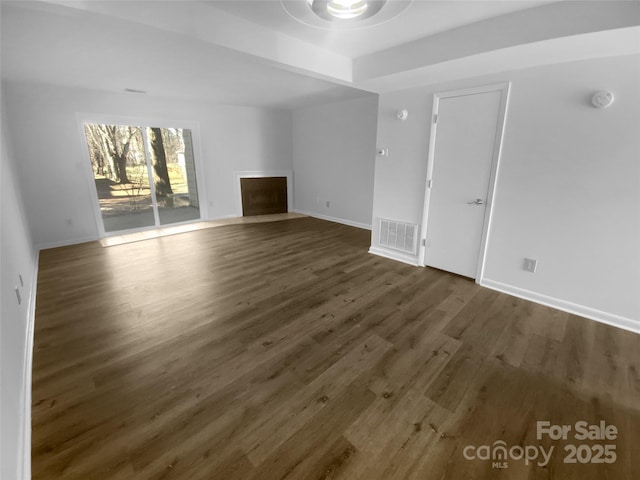 unfurnished living room featuring a fireplace with flush hearth, dark wood finished floors, visible vents, and baseboards