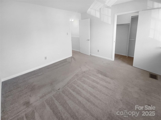 spare room with carpet floors, baseboards, and visible vents