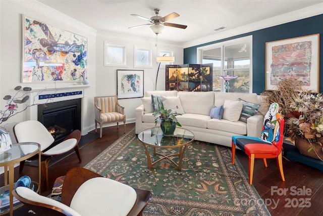 living room with dark wood-style floors, a glass covered fireplace, and crown molding