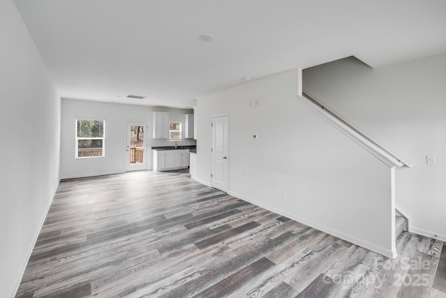 unfurnished living room with visible vents, baseboards, and wood finished floors