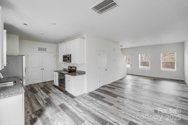 kitchen featuring open floor plan, stainless steel appliances, visible vents, and white cabinetry